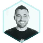 Smiling man with short dark hair and a trimmed beard, wearing a dark T-shirt, shown inside a light blue hexagon frame on a white background, representing AppSec Risk Prioritization and Runtime Vulnerability Detection.