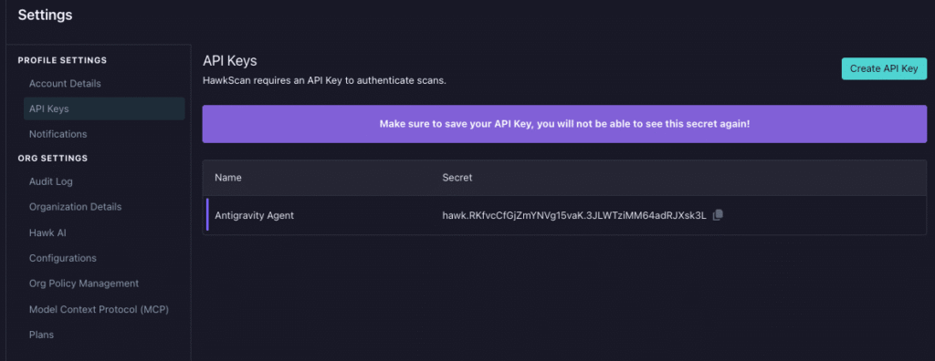 A dark-themed settings page displays the API Keys section. A warning banner about Claude Code Security highlights the need to save your API key. One key named Antigravity Agent is shown, with its secret partially visible and a copy icon beside it.